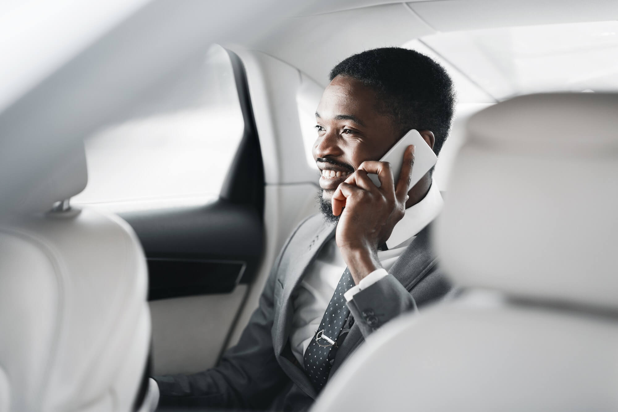 Happy afro businessman talking on cellphone in car