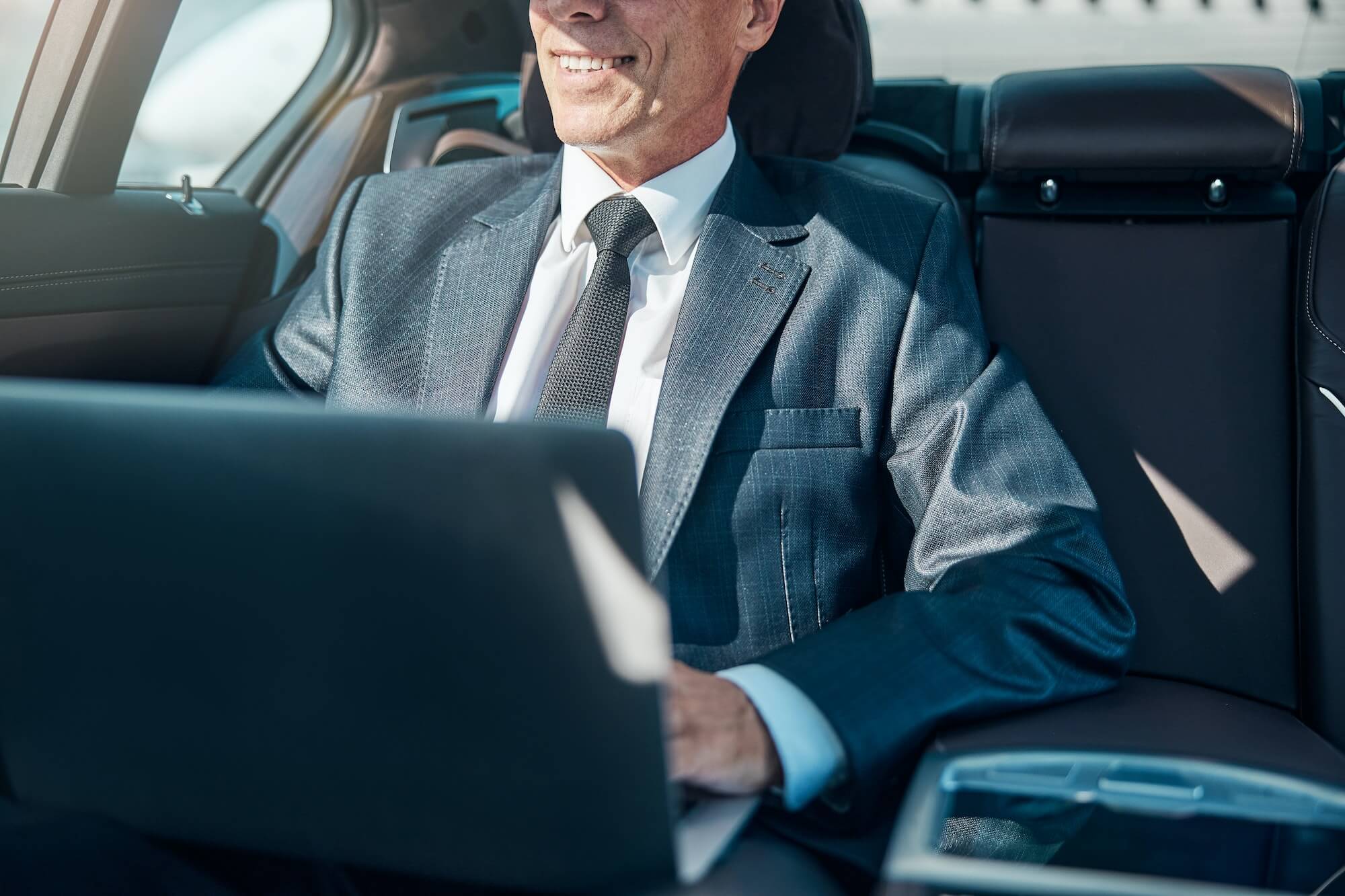 Cheerful elegant man with laptop in car