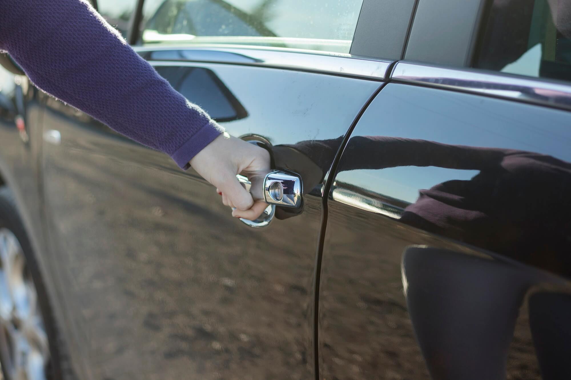 Close-up of woman hand opening a car door.