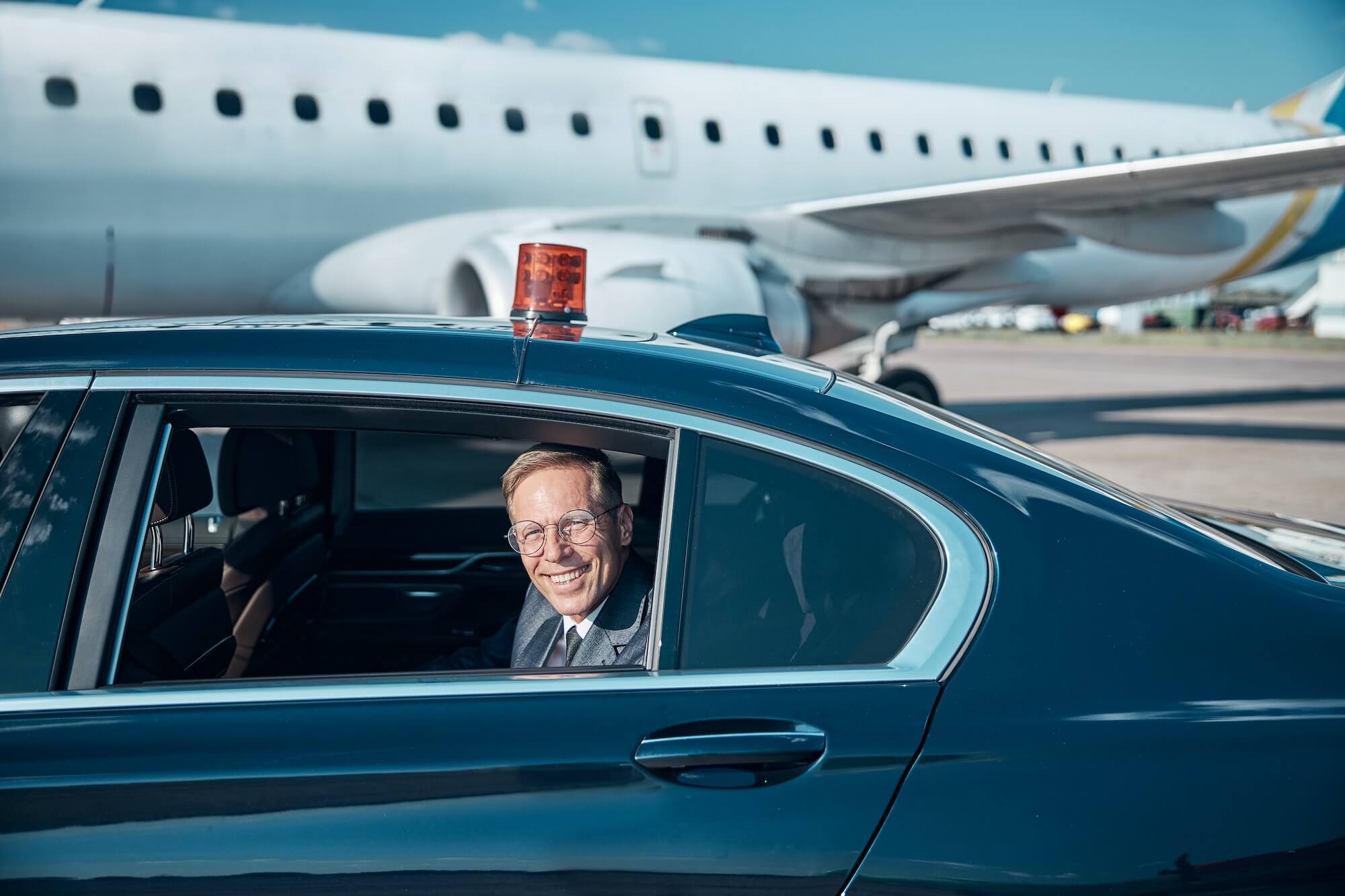 Happy elegant man coming to plane by car
