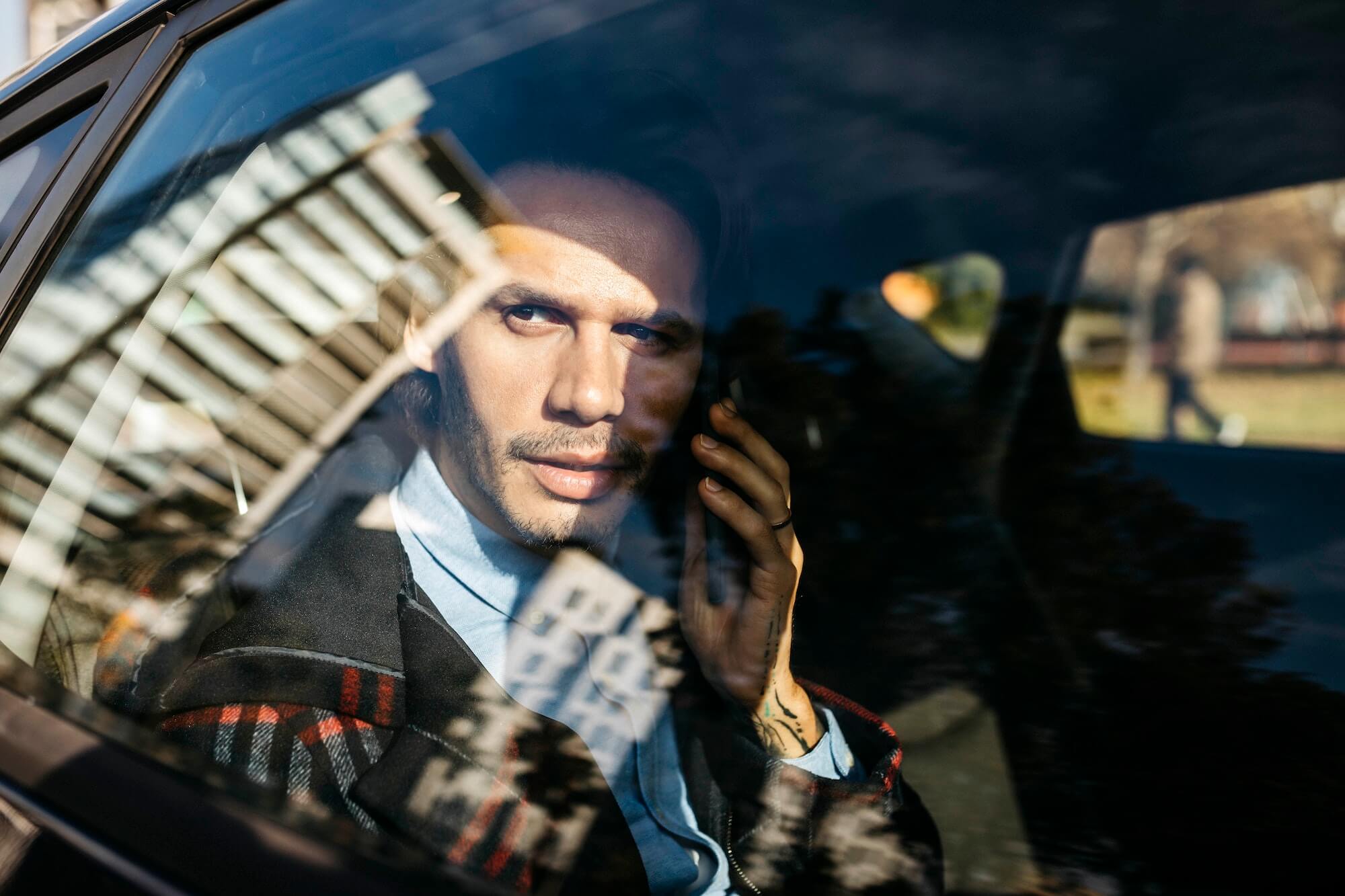 Man sitting on back seat of a car talking on cell phone