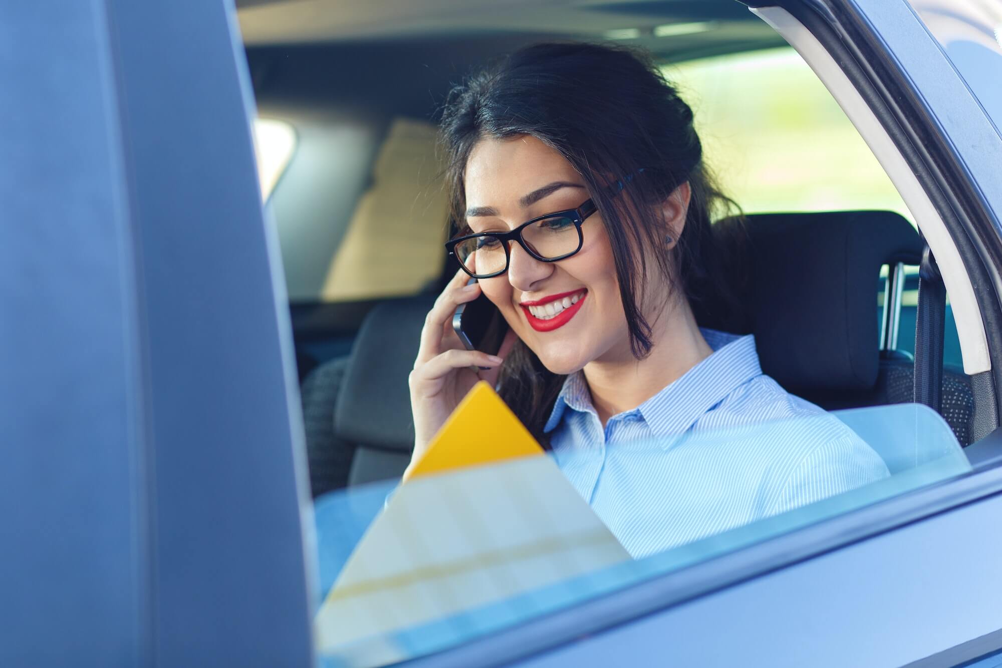 Business woman sitting in the car and using phone.