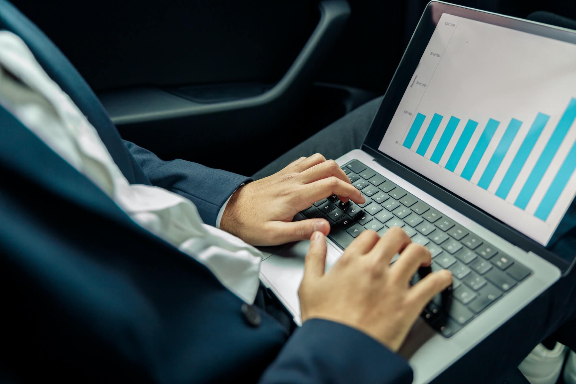 Close up of businessman in suit studies charts and statistics while riding in car