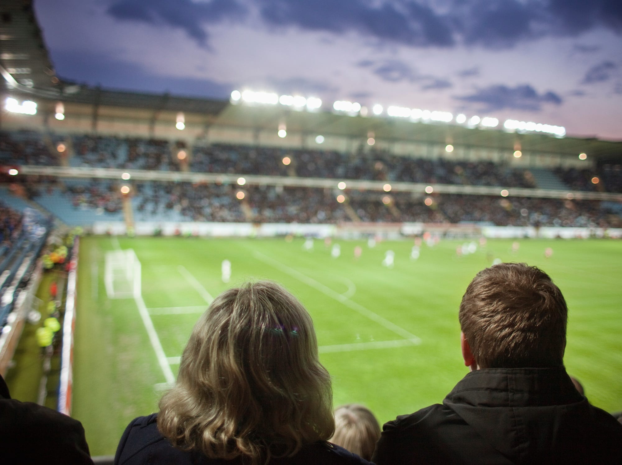 Rear view of people watching soccer match at stadium