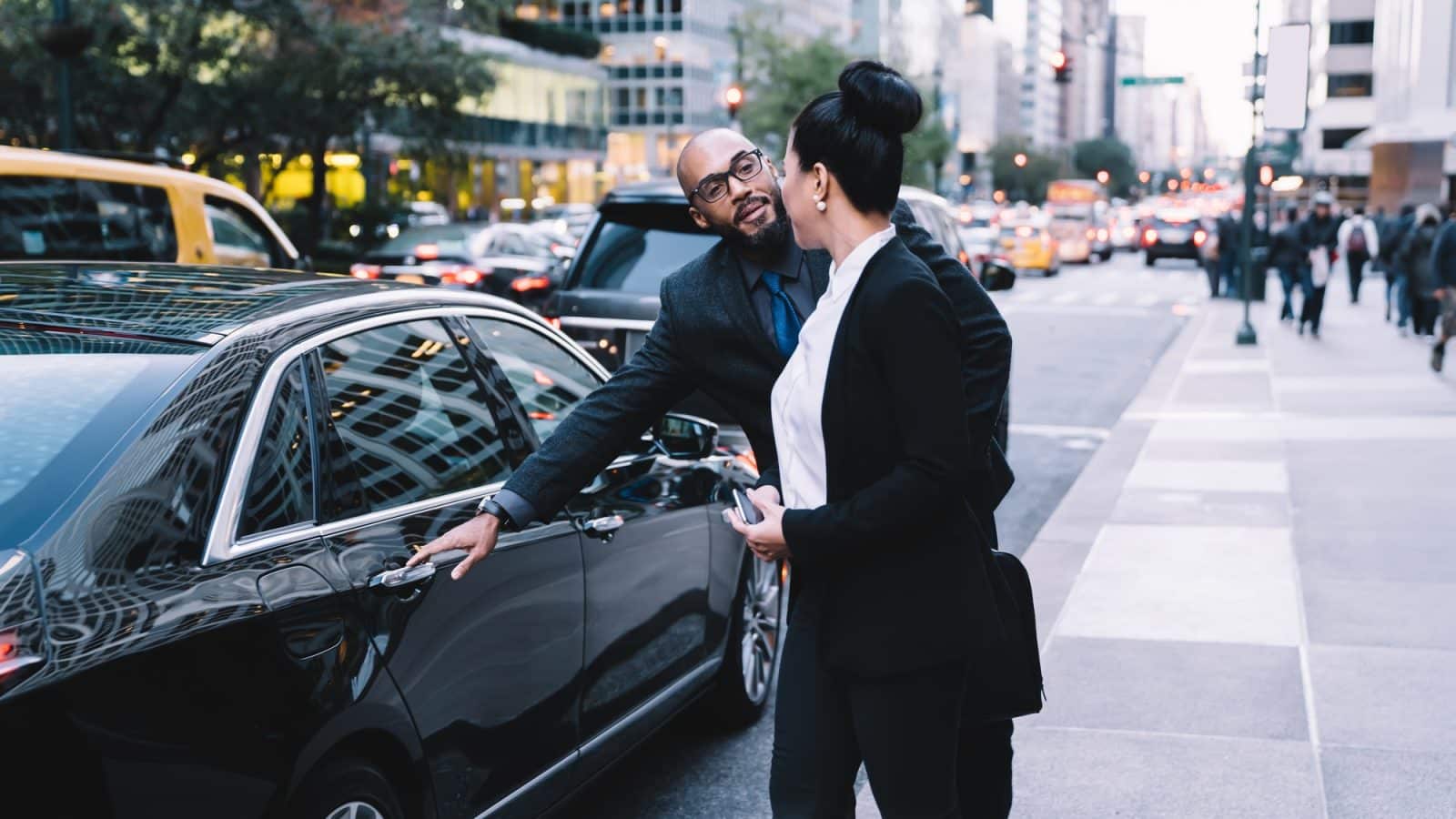 Cheerful multiracial colleagues taking corporate car